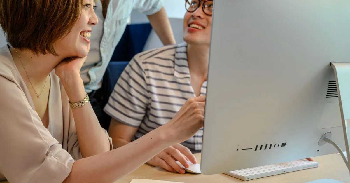 Un groupe diversifié de collègues collaborant devant un ordinateur dans un environnement de bureau moderne.