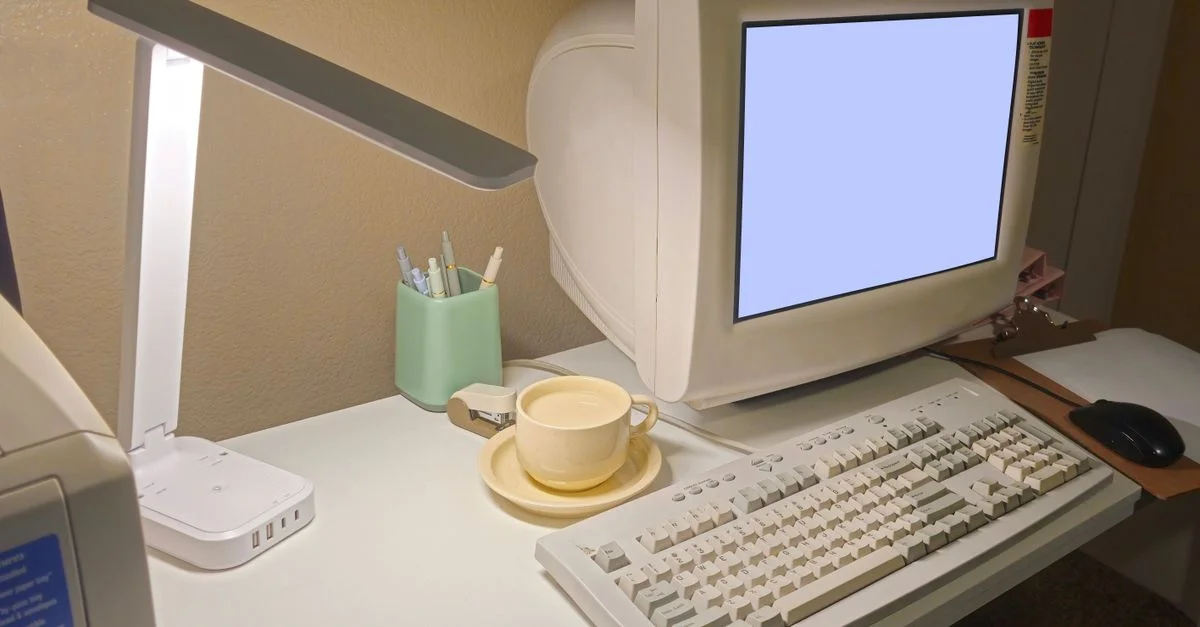 Un bureau à domicile empreint de nostalgie, avec un ordinateur, un clavier et une tasse à café vintage.